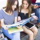 cheerful-women-studying-bench-near-friends